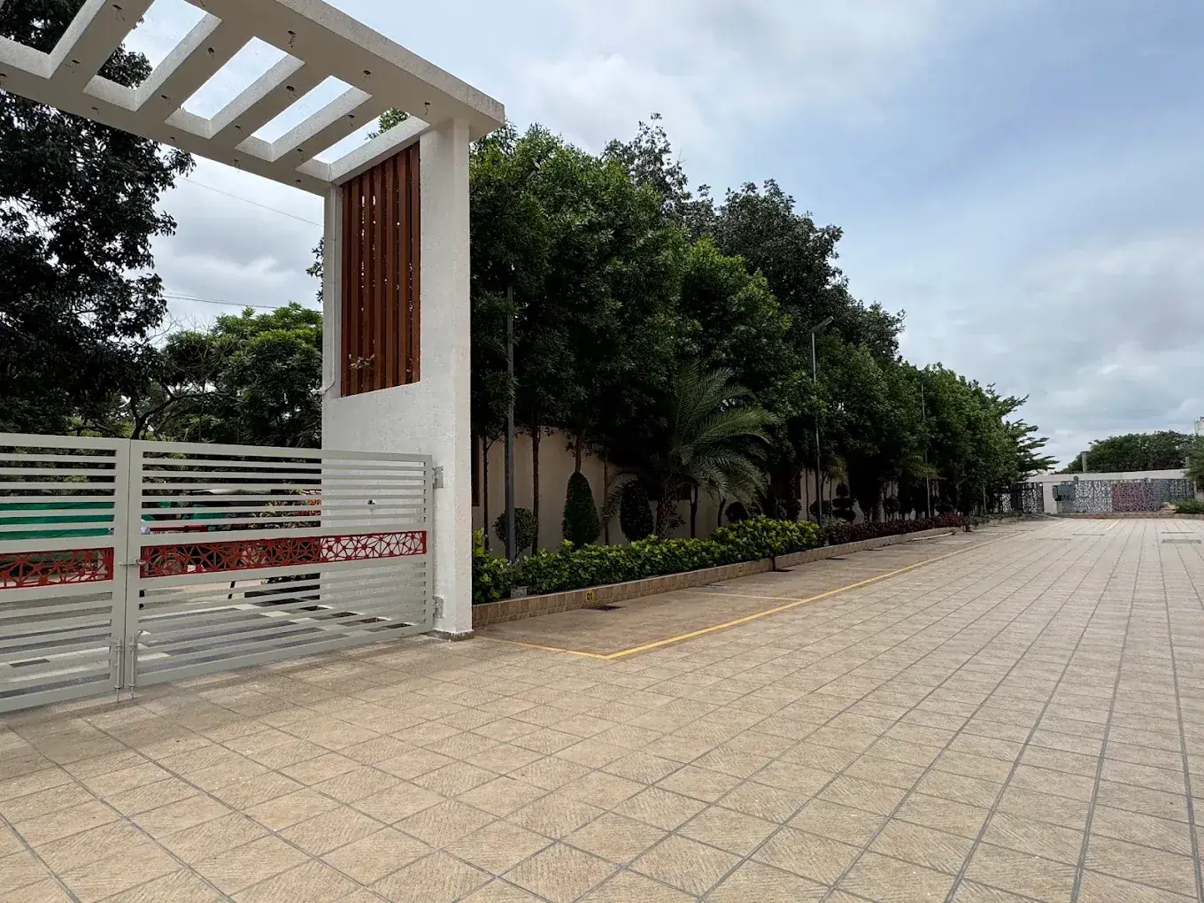 Premia entrance gate and paved driveway lined with landscaped trees, Jakkur (real photo)